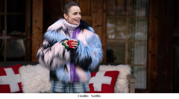 A person in a fur coat holding a red cupDescription automatically generated