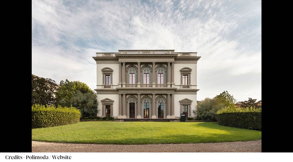 A large white building with a lawn and trees
Description automatically generated