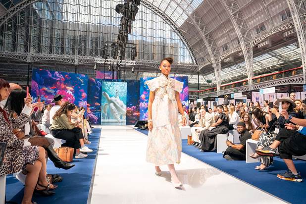 A person walking down a runway in a building with people sitting on the floor

AI-generated content may be incorrect.