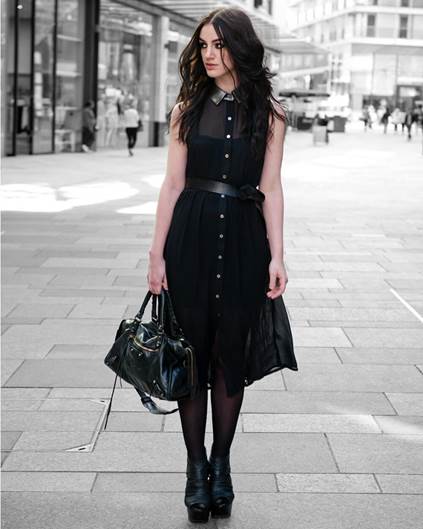 A person wearing a black dress and holding a purseDescription automatically generated with medium confidence