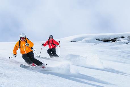A couple of people skiing down a mountainDescription automatically generated with medium confidence