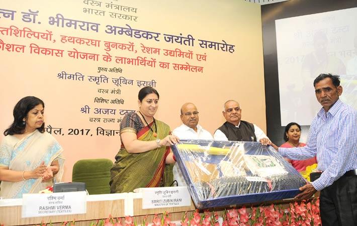 Textiles minister Smriti Irani and minister of social justice & empowerment, Thaawar Chand Gehlot, and other dignitaries presenting tool kits to SC handicrafts artisans. Courtesy: PIB